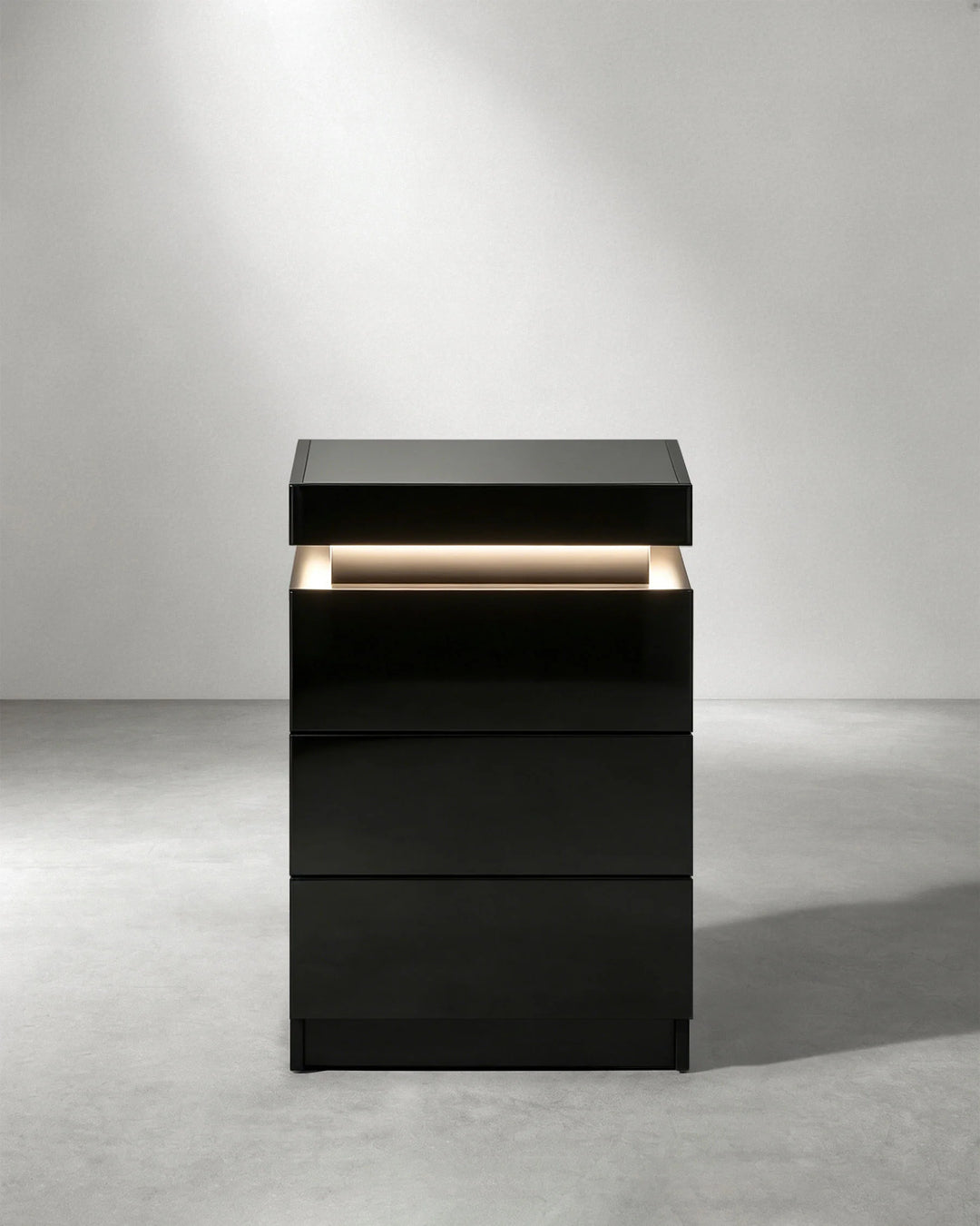 Front view of black Kumar LED bedside table with three drawers and integrated ambient lighting