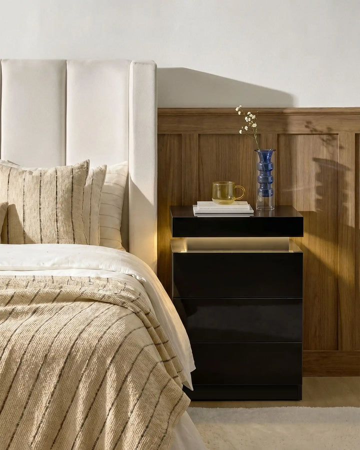 Front view of black Kumar LED bedside table with integrated warm LED light, high gloss bedside cabinet in a modern bedroom