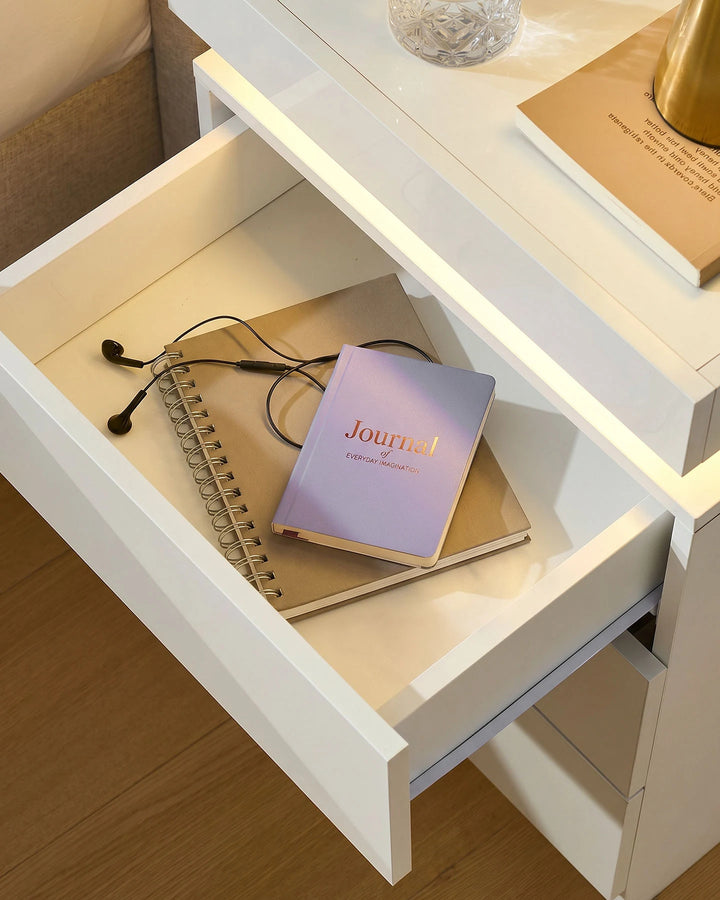 Close-up of an open drawer on the white smart nightstand showing internal storage space.