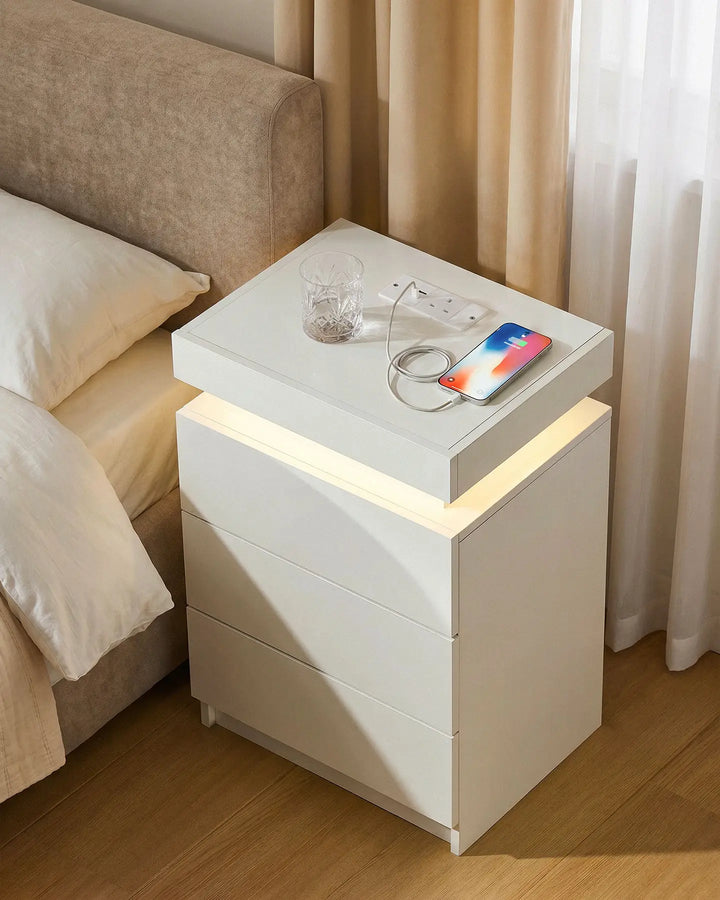 Overhead view of the white bedside table with a phone and glass, showing the ambient glow.
