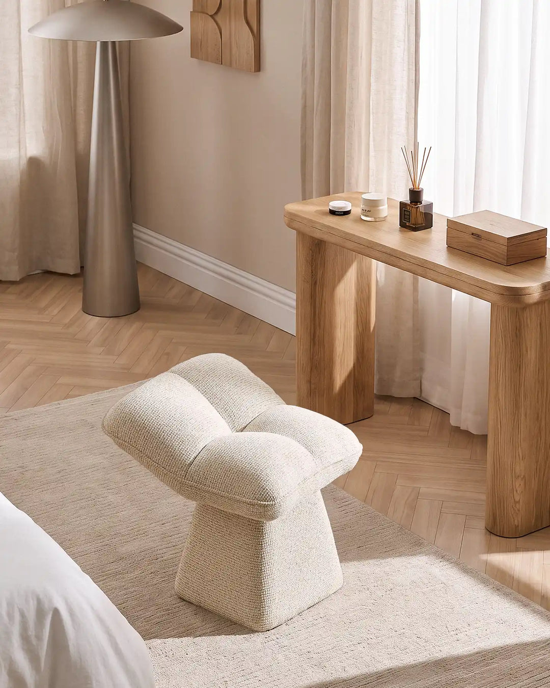 Liora beige swivel vanity stool placed beside a wooden dressing table in a bright bedroom, complementing the neutral interior and natural wood flooring