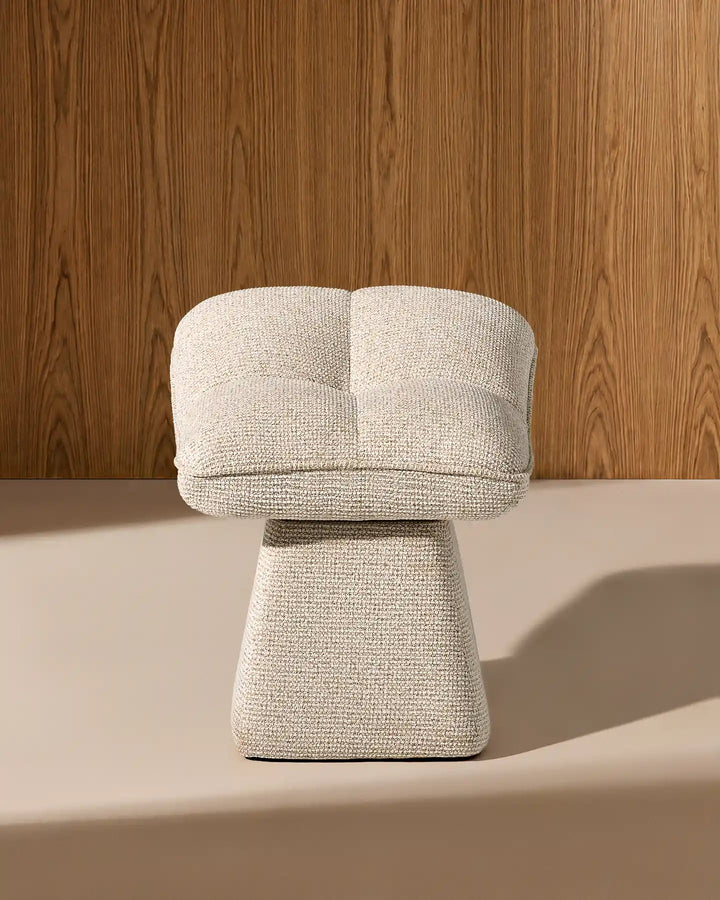 Front view of the Liora beige swivel vanity stool showing its softly curved padded seat, textured upholstery and sculptural tapered base