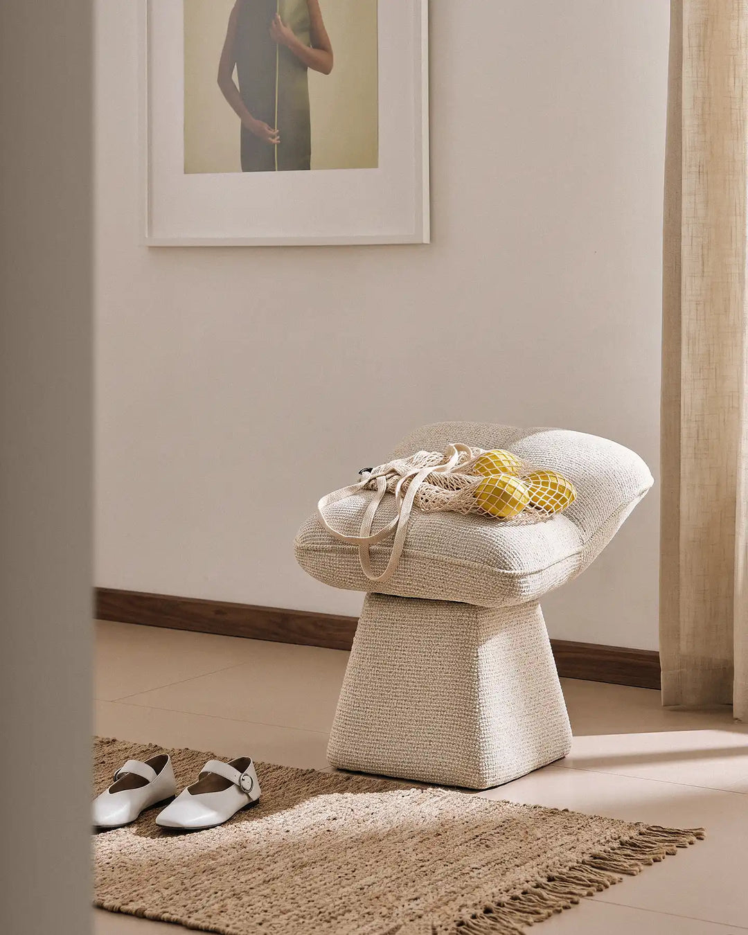 Liora beige swivel vanity stool used as an entryway seat in a warm hallway, with a bag of lemons placed on the cushioned seat