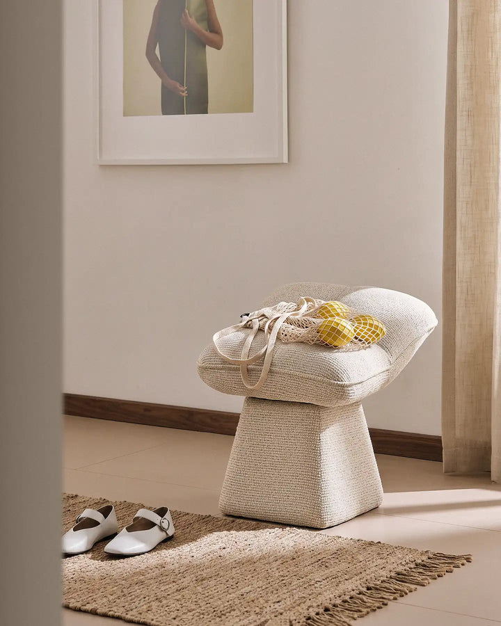 Liora beige swivel vanity stool used as an entryway seat in a warm hallway, with a bag of lemons placed on the cushioned seat