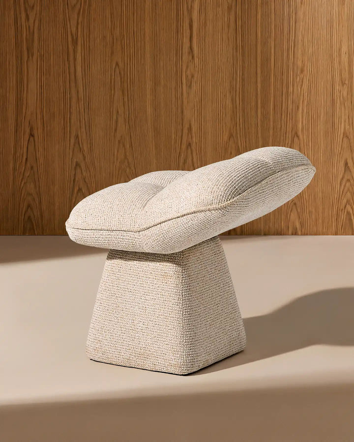 Side view of the Liora beige swivel vanity stool highlighting its curved seat profile and distinctive sculptural pedestal base