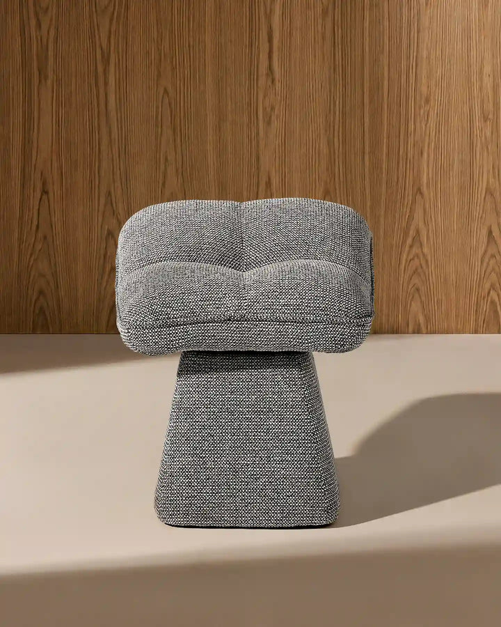 Front view of the Liora grey swivel vanity stool showing its softly curved padded seat, textured upholstery and sculptural tapered base