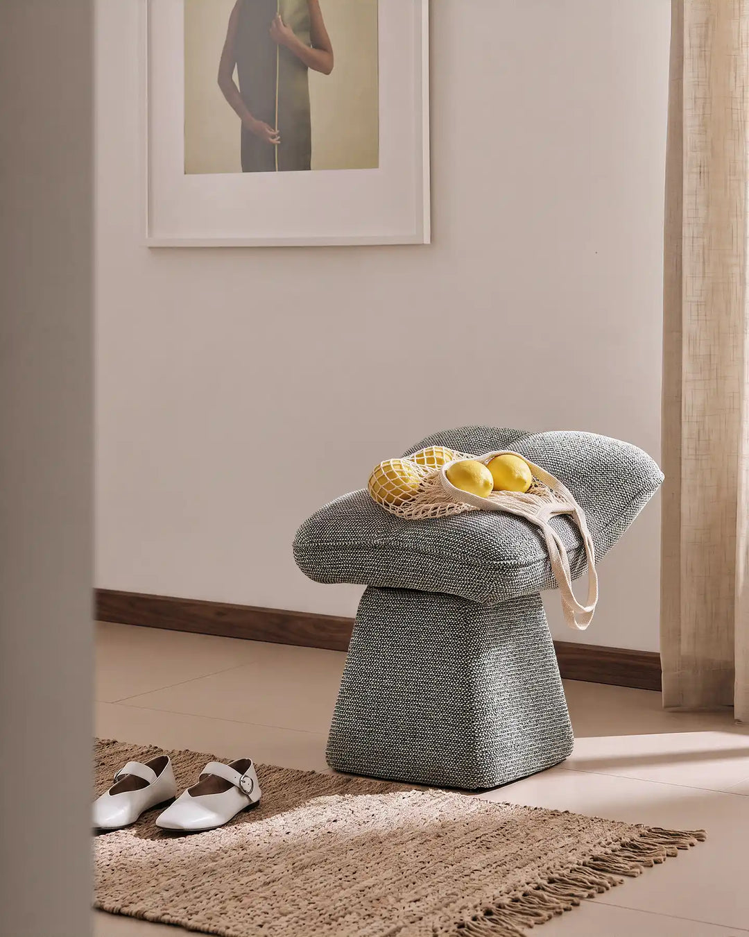 Liora grey swivel vanity stool used as an entryway seat in a warm hallway, with a bag of lemons placed on the cushioned seat