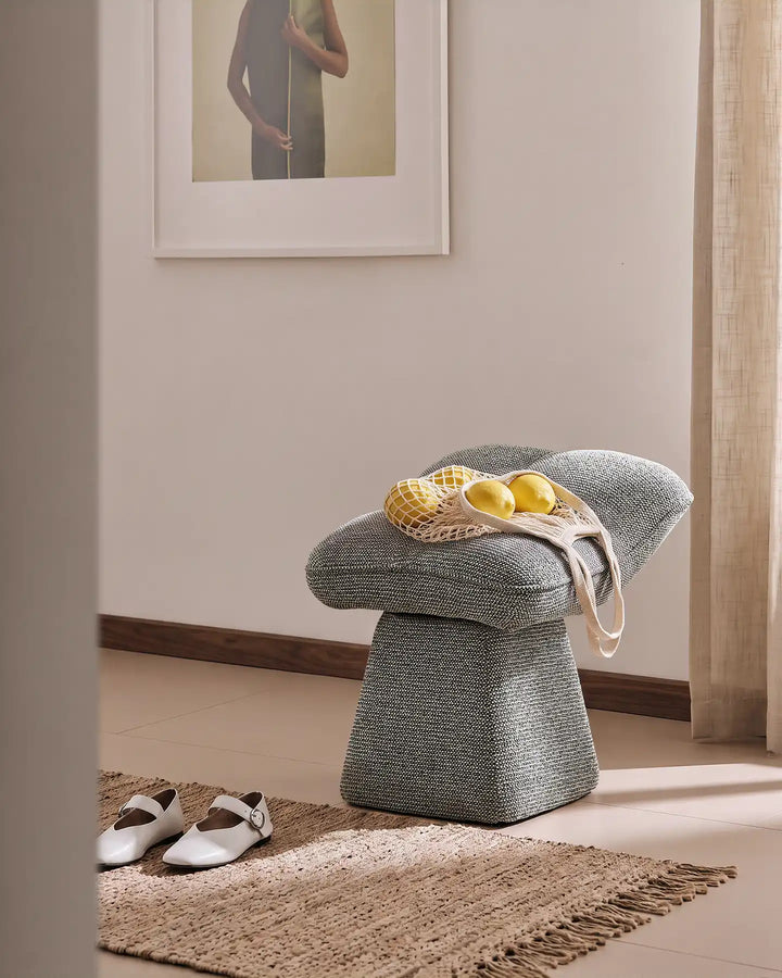 Liora grey swivel vanity stool used as an entryway seat in a warm hallway, with a bag of lemons placed on the cushioned seat