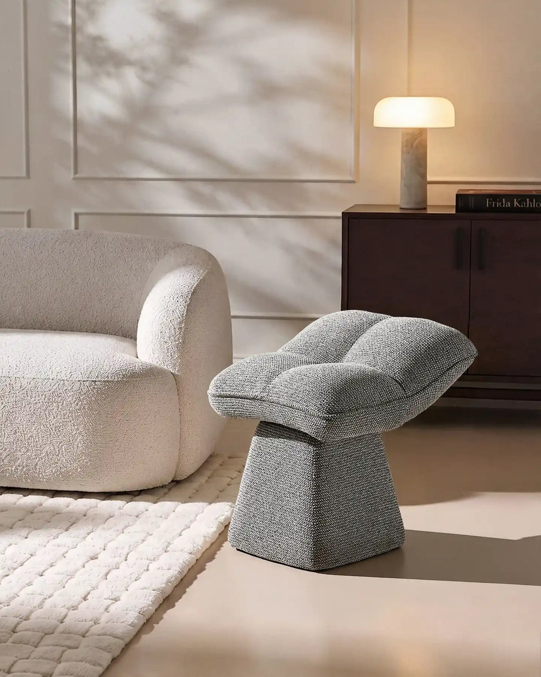 Liora grey swivel vanity stool paired with a curved upholstered chair and rug in a contemporary neutral living space
