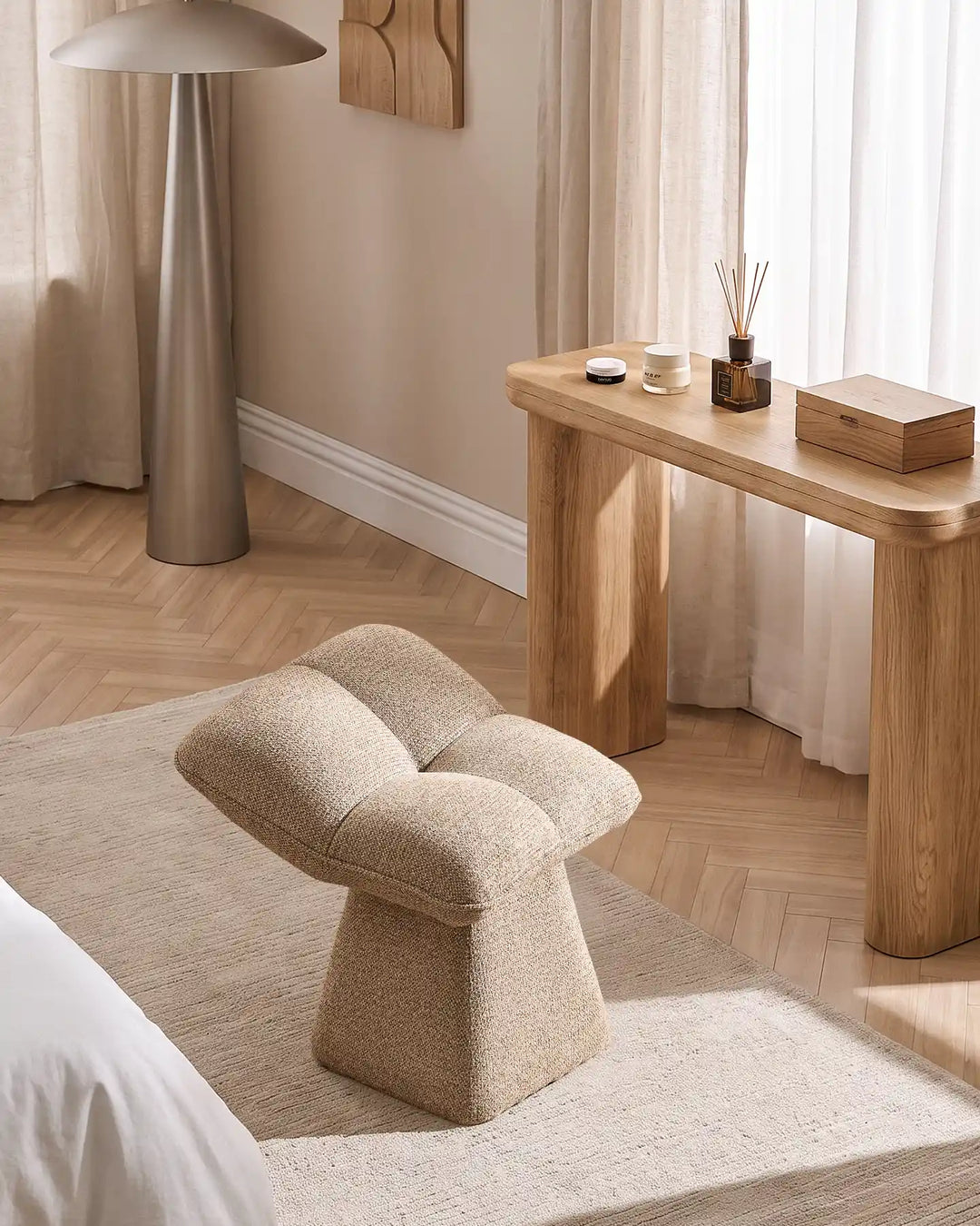 Liora khaki swivel vanity stool placed beside a wooden dressing table in a bright bedroom, complementing the neutral interior and natural wood flooring