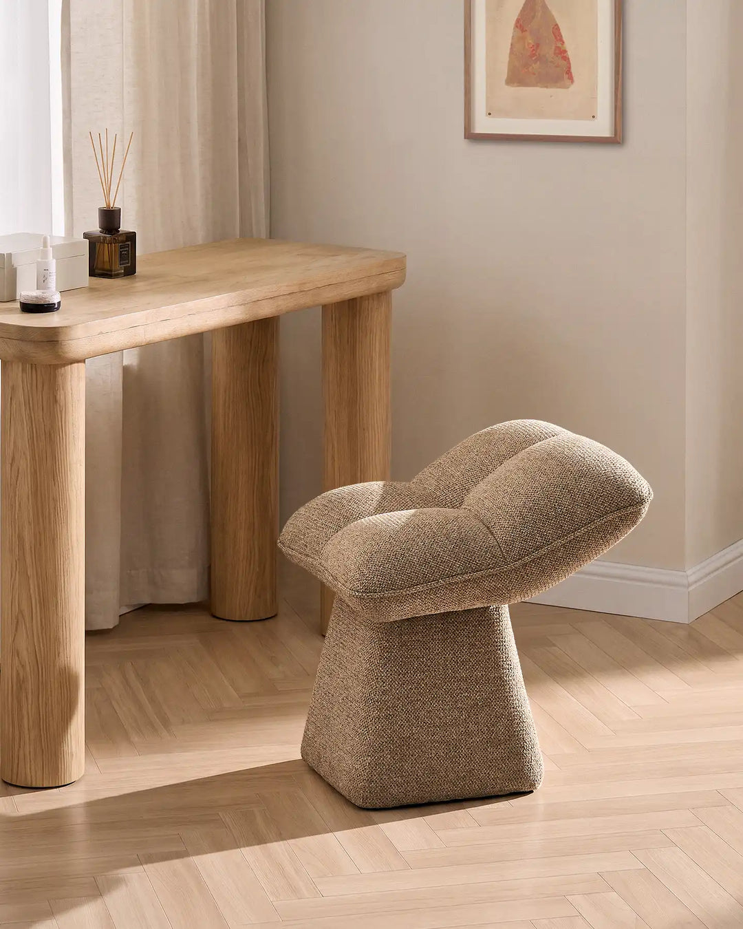 Liora khaki swivel vanity stool styled beside a wooden console table in a warm neutral bedroom, featuring a softly padded seat and sculptural pedestal base