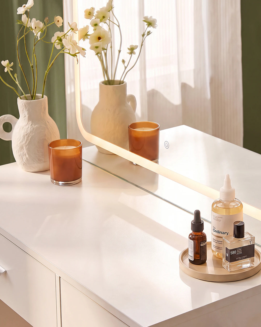 Close-up of the Luna dressing table surface styled with decorative vases and accessories beside a bright window.