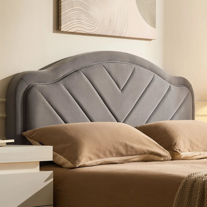 Close-up of grey velvet upholstered headboard on double bed frame with soft texture and V-stitch detail