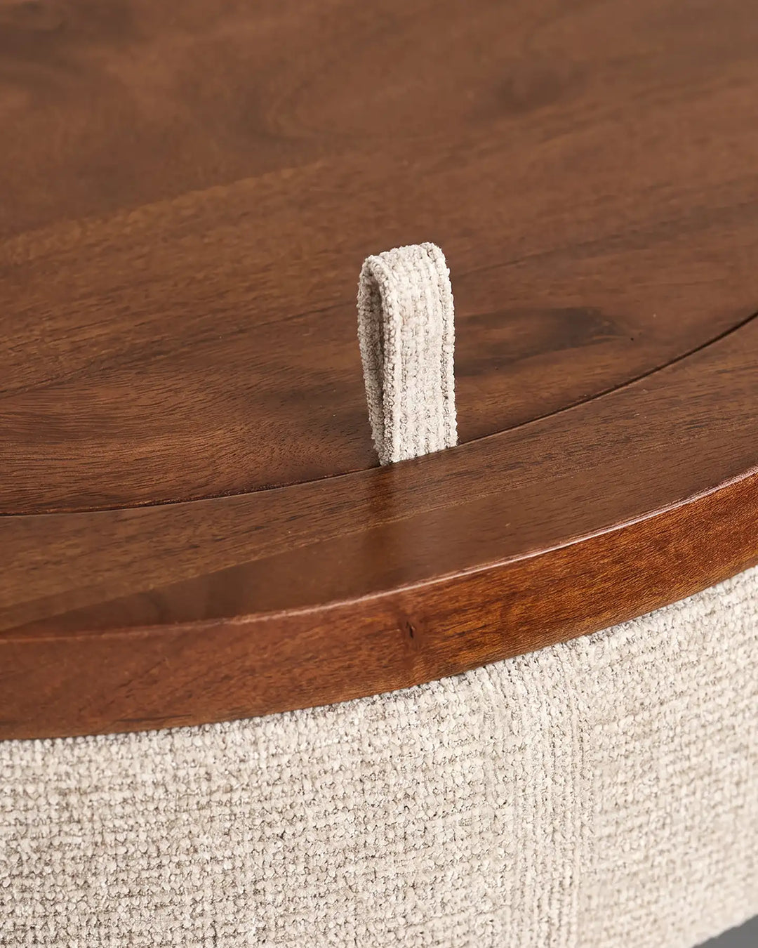 Close-up of the wooden handle on the Mina dressing table, set against textured cream chenille upholstery and a rounded wooden tabletop