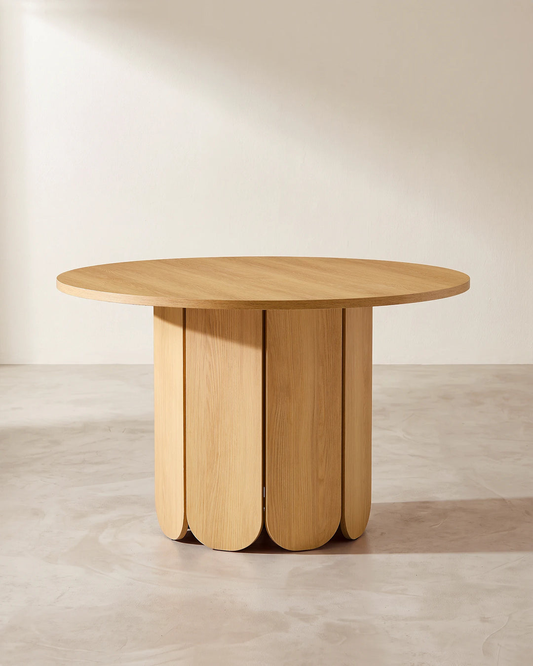Nara round dining table featuring a distinctive oak-effect pedestal base with rounded vertical panels and a minimalist silhouette