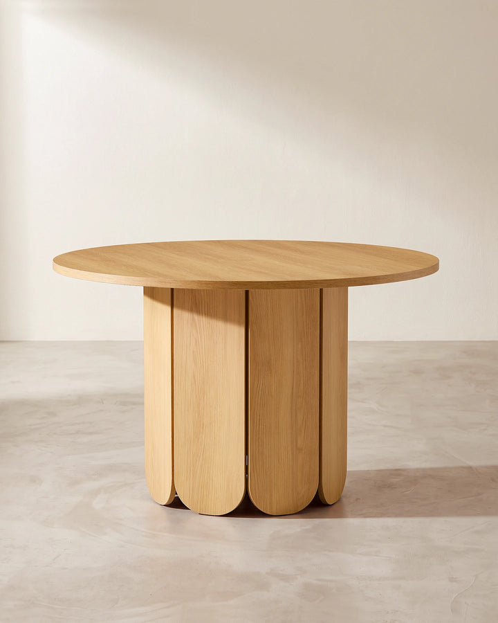 Nara round dining table featuring a distinctive oak-effect pedestal base with rounded vertical panels and a minimalist silhouette