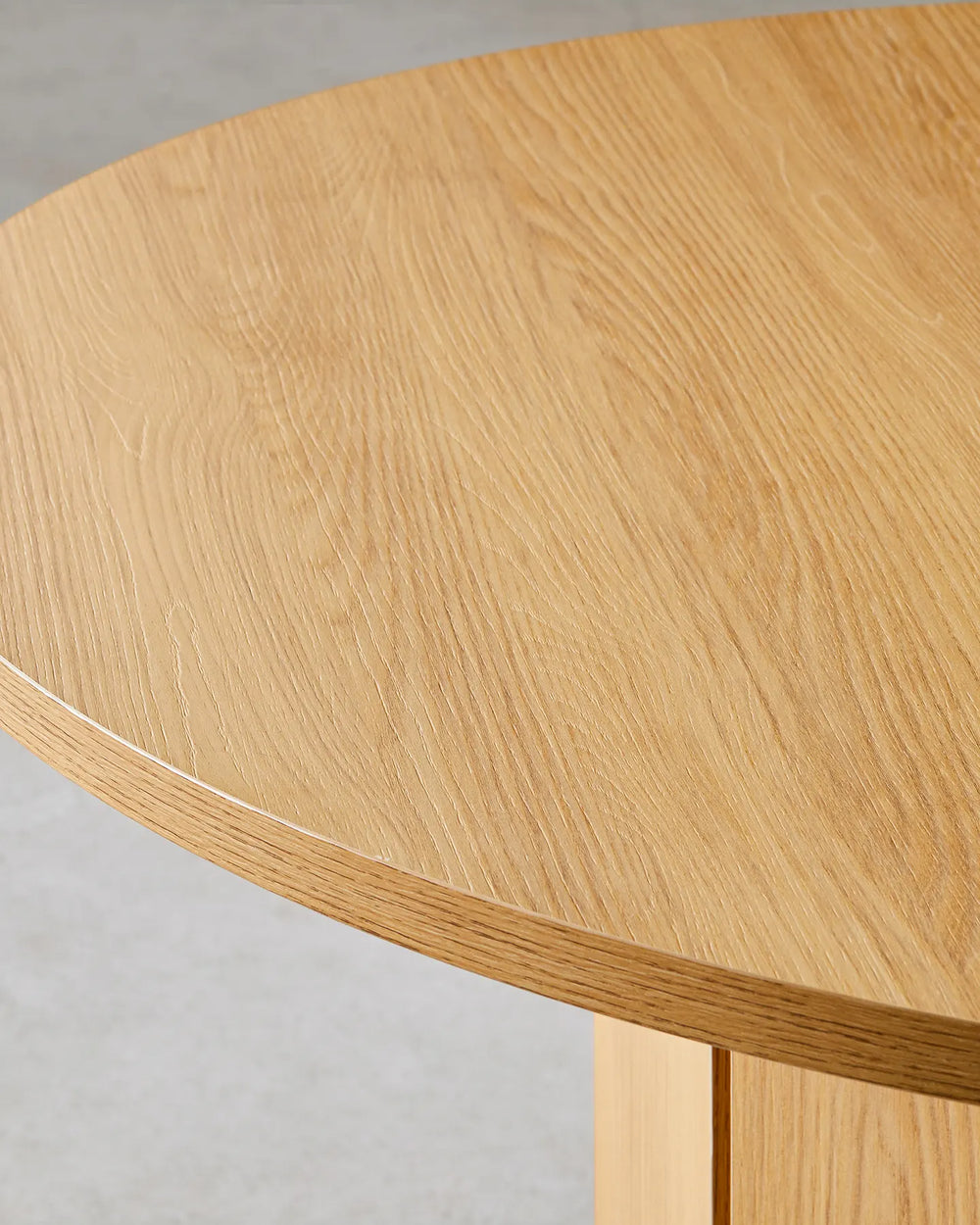 Close-up of the Nara dining table's natural oak-effect tabletop, highlighting the warm wood grain and smooth rounded edge