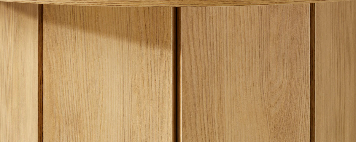 Close-up of the Nara dining table's pedestal base, highlighting the vertical panel design, subtle seams and oak-effect wood grain