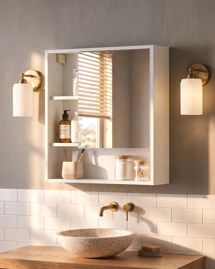 White mirrored bathroom cabinet above a ceramic basin, paired with warm brass wall lighting and natural wood accents for a contemporary bathroom.