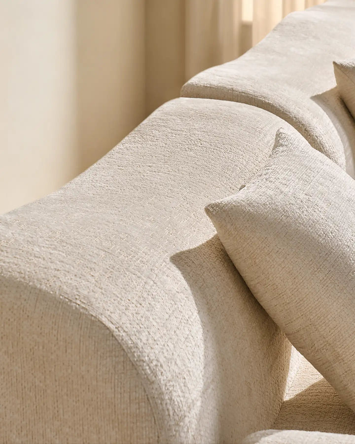Detail shot of the Nola modular sofa's rounded armrest and plush, padded backrest.