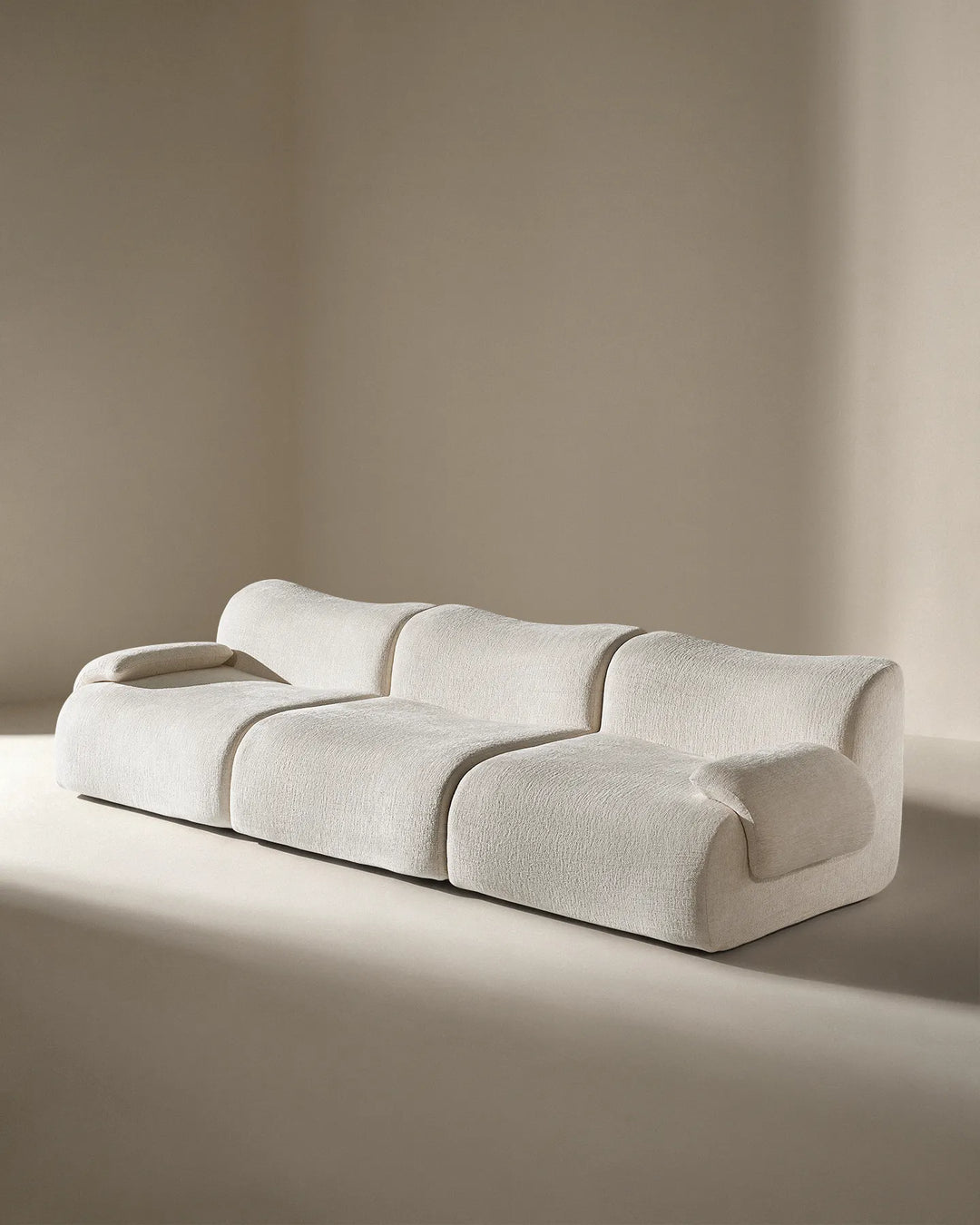 Angled studio shot of the Nola sectional, showing the deep-tufted style and modern curves.