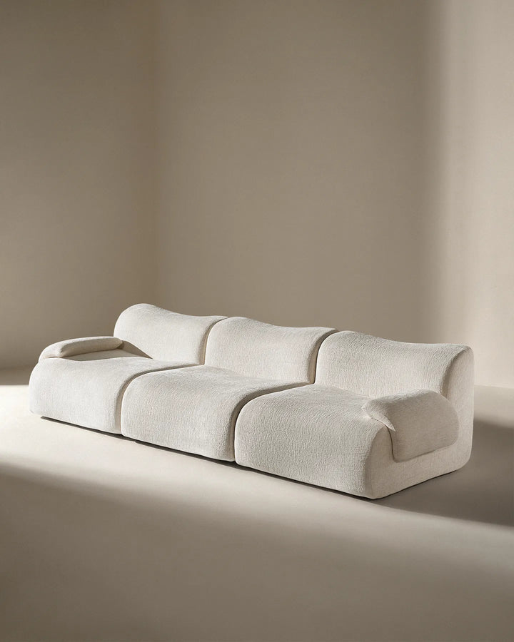 Angled studio shot of the Nola sectional, showing the deep-tufted style and modern curves.