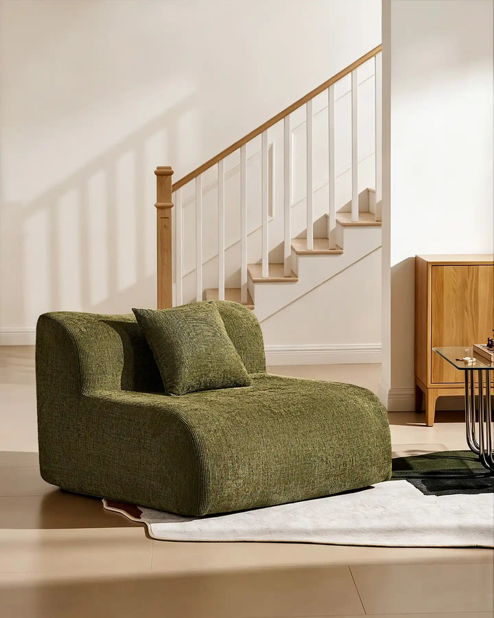 The Nola middle modular section used as an accent armchair, featuring a matching cushion in green chenille fabric.