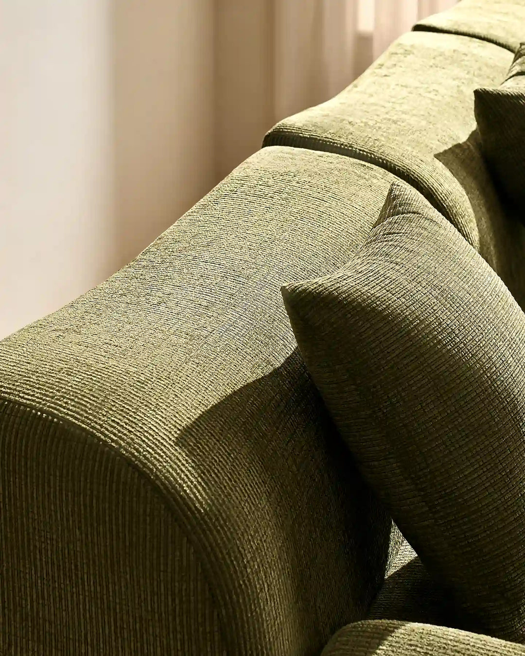 Detail shot of the Nola modular sofa's rounded armrest and plush, padded backrest.