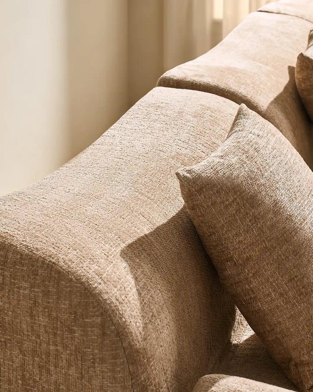 Detail shot of the Nola modular sofa's rounded armrest and plush, padded backrest.
