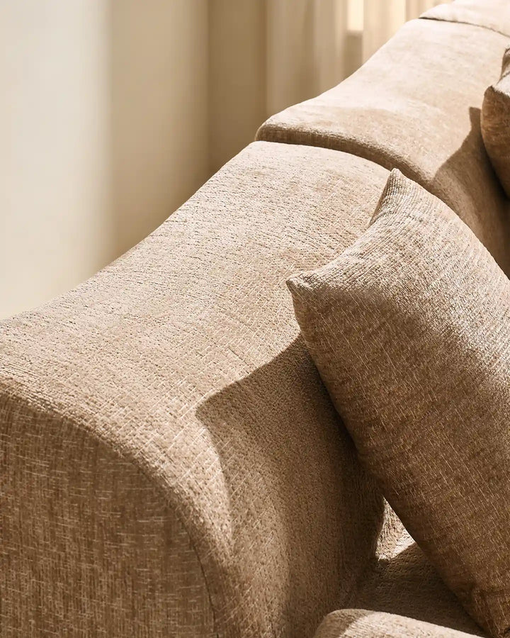 Detail shot of the Nola modular sofa's rounded armrest and plush, padded backrest.