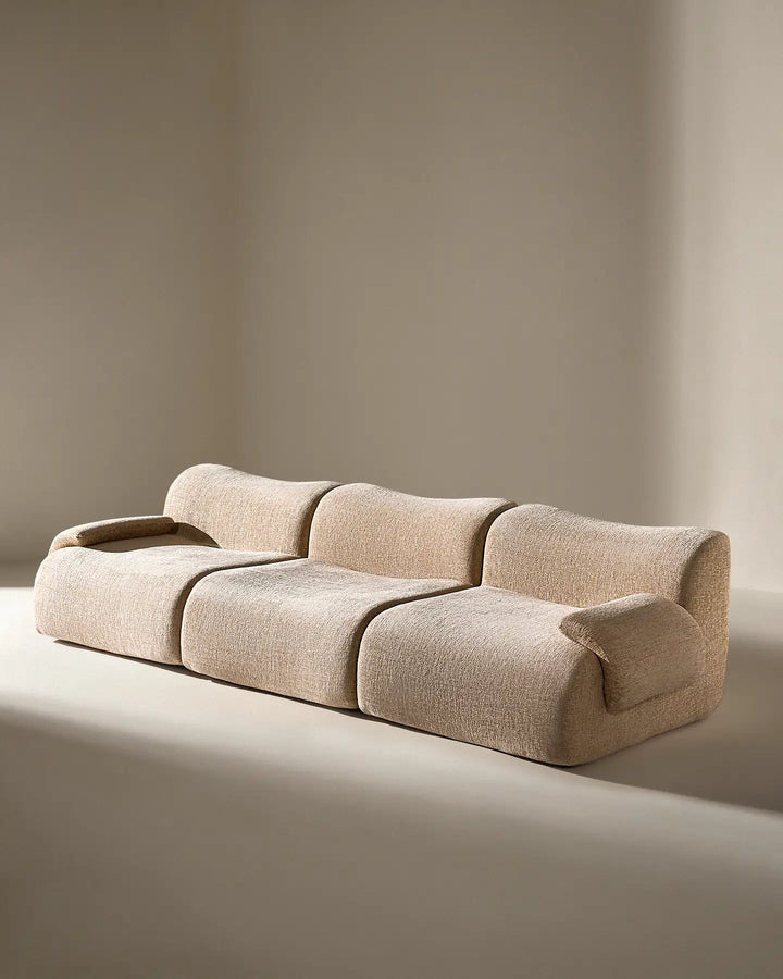 Angled studio shot of the Nola sectional, showing the deep-tufted style and modern curves.