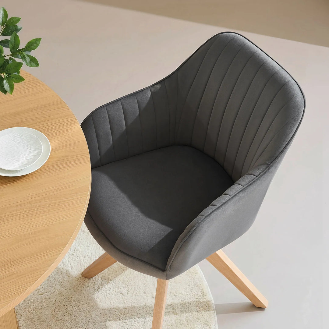 Single grey Oakley swivel chair at a dining table, featuring a bucket-style seat and stitched back for comfort and minimalist style