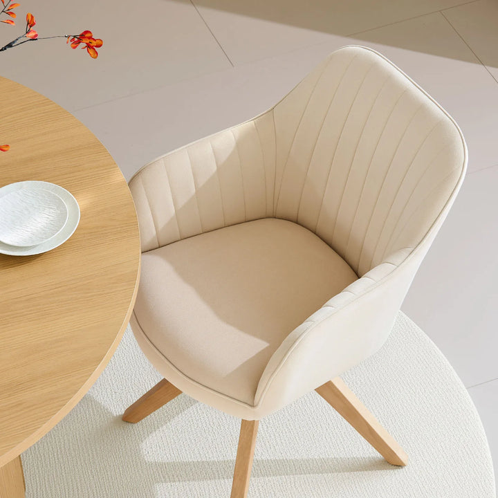 Single beige Oakley swivel chair at a dining table, featuring a bucket-style seat and stitched back for comfort and minimalist style