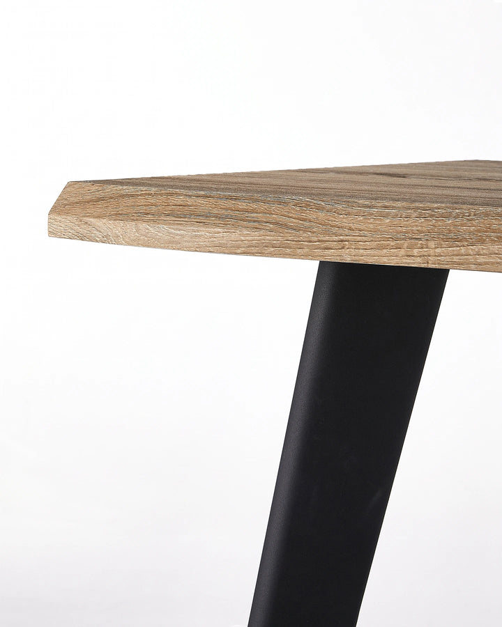 Close-up of the Seibold dining table showing the natural wood-effect tabletop edge and black tapered leg