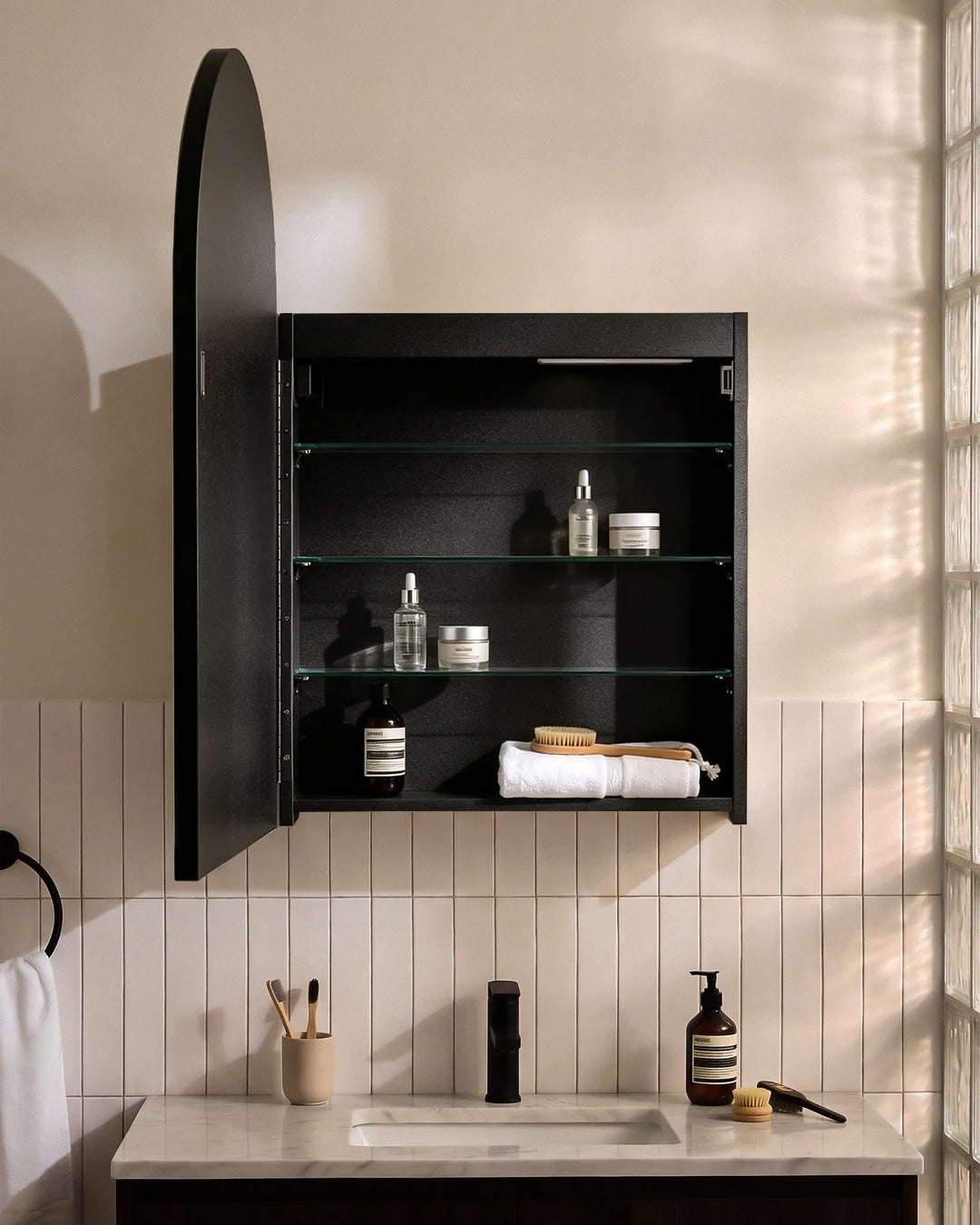 Open black Arcadia arched mirror cabinet showing spacious glass shelves for toiletries.